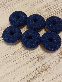 six blue donuts sitting on top of a white wooden table with sprinkles