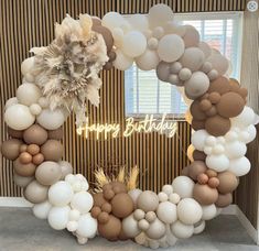 a happy birthday balloon arch with white, brown and beige balloons in the shape of a heart