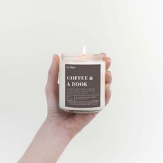 a hand holding a candle that says coffee & a book on the front and side