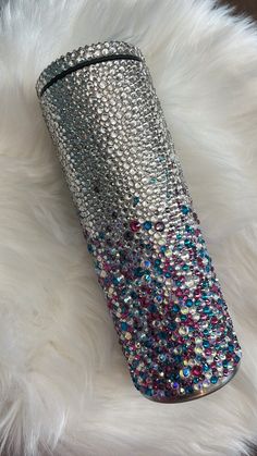 a silver and multicolored tumbler sitting on top of a white fur covered floor