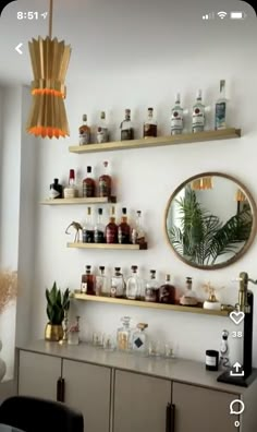 a room with shelves filled with bottles and glasses on top of each shelf in front of a mirror