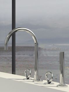 two chrome faucets sitting next to each other on a counter top near the ocean