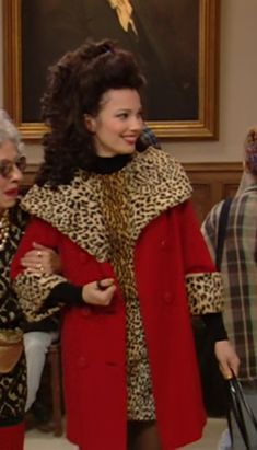 two women dressed in animal print and red coats, one holding a handbag while the other holds a purse