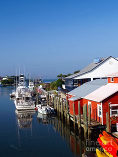 several boats are docked in the water next to red buildings and white trimmings