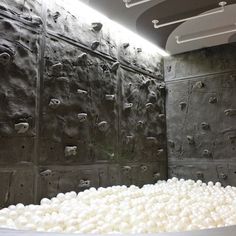 an indoor climbing wall with white balls in the foreground and black rock walls behind it