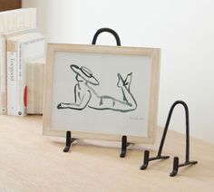 a drawing is sitting on a shelf next to two books and a pair of black hooks