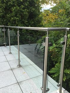 a glass and metal railing on top of a building with trees in the back ground