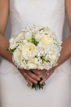 a bride holding a bouquet of white flowers