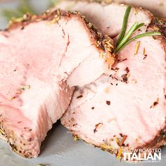 two slices of roast beef on a plate with rosemary garnish and seasoning