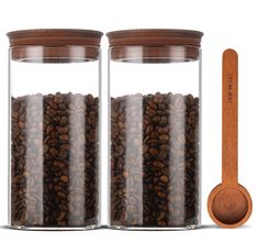 two glass jars filled with coffee beans next to a wooden spoon