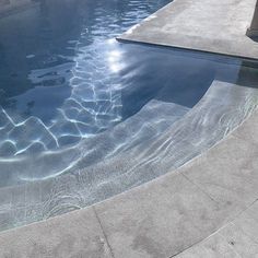 an empty swimming pool with clear water and sun reflecting off the side of the pool