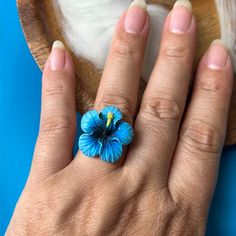 a woman's hand with a blue flower ring on her left hand, next to a wooden bowl