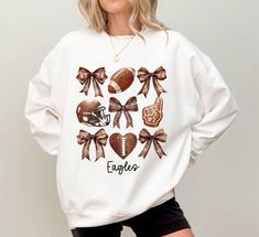 Custom Football Coquette Bow Sweatshirt,Football Mom Sweatshirt, Football Season,Game Day Sweatshirt, Football Team Sweatshirt, Coquette Aesthetic, Hi! Welcome to the 💍 Lord Of The Shirt 💍 store.  We offer a wide range of unique designs tailored specifically for you. Please take a look at the other products in my shop! Our sweatshirts are made of a thick cotton and polyester blend that provides both comfort and style. There are no side seams and the air-jet yarn ensures a softer feel and less pilling. Plus, our sweatshirts have double needle stitching on the shoulders, armhole, neck, waistband and cuffs. If you prefer a comfortable fit, we recommend increasing the size by one. If you prefer a slim fit, please choose a smaller size. Follow the steps below to place your order: 💍 Choose yo Varsity White Sweatshirt For Football Season, White Sports Fan Sweatshirt For Fall, White Sweatshirt For Football Season Game Day, White College Sweatshirt For Football Season, White Graphic Print Sweatshirt For Football Season, Sporty Sweatshirt For Football Season Cheerleading, White Sublimation Design For Football Season Game Day, White Sweatshirt With Sublimation Print For Sports Season, White Football Season Sweatshirt With Letter Print