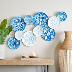 blue and white plates hanging on the wall next to a vase with a plant in it