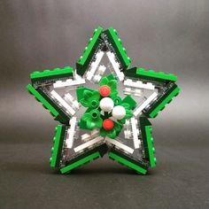 an ornament made out of legos on a gray surface with red and white balls in the center