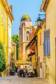 an alley way with yellow buildings and a church in the background