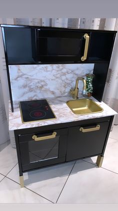 a small kitchen with black cabinets and gold accents on the countertop, along with a sink