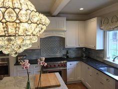 a kitchen with white cabinets and marble counter tops, an island in the middle has flowers on it