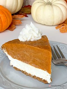 a slice of pumpkin pie sitting on top of a plate next to two pumpkins