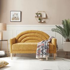 a living room with a yellow couch and potted plants on the side table in front of it