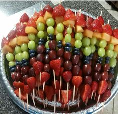 a platter filled with grapes, strawberries and other fruit on skewers