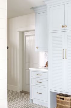 a kitchen with white cupboards and tile flooring next to a wall mounted oven