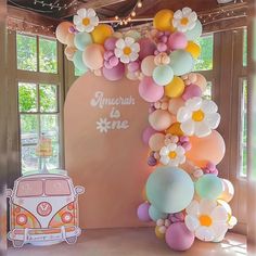 an arch made out of balloons and flowers with a vw bus in the background