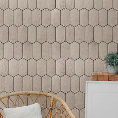 a wicker chair sitting in front of a wall with hexagonal tiles on it