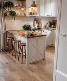 a kitchen with white cabinets and wooden counter tops, an island in between two stools