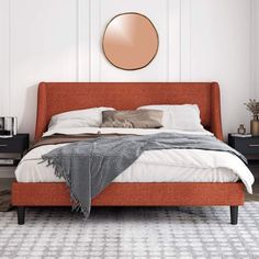 a bed with an orange headboard and pillows in a white room next to a wall