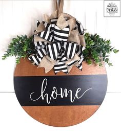 a wooden sign with the word home painted on it next to a planter filled with greenery