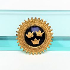 This is a nice vintage brooch by Sporrang & Co., Sweden.The piece is made of gold filled metal in a disc shape.  The center is set with a cobalt blue enameled cabochon decorated with three crowns.The brooch is in very nice vintage condition with some light wear to the back consistent with age and use.The brooch measures 1.3" wide.If you have any questions or would like to see additional pictures, please contact us before making your purchase.Buyers outside the United States, please contact u Art Deco Era, Vintage Brooch, Color Crystal, Rough Cut, Flower Brooch, Cut Glass, Vintage Brooches, Vintage Signs, Cobalt Blue