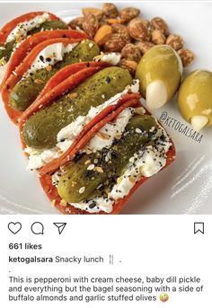 a plate topped with stuffed peppers and olives next to some nuts on the side