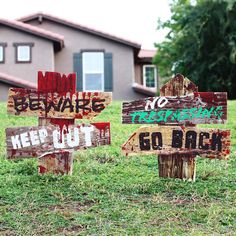 several wooden signs in front of a house that says beware, keep out, go back