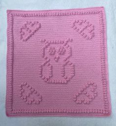 a pink crocheted square with an owl on it