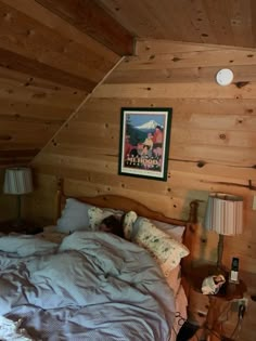 a bed in a room with wood paneling and a painting on the wall above it