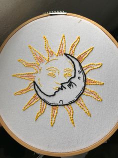 a hand embroidered sun and moon on a white fabric with yellow thread in the middle