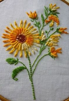 a close up of a embroidery on a white cloth with orange and yellow flowers in it