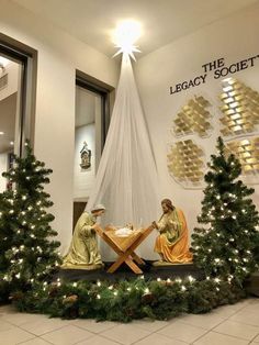 two statues of jesus and mary in front of a christmas tree