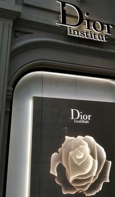 the dior boutique sign is lit up with white lights and a rose on it