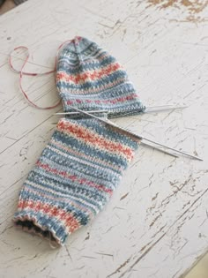 a knitted mitt sitting on top of a white table next to some scissors