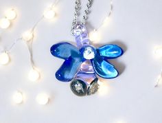 a blue flower necklace on a chain with lights in the backgroung behind it