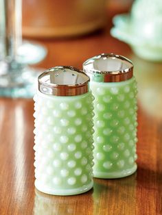 two salt and pepper shakers sitting on top of a wooden table