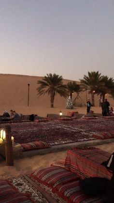 people are sitting in the desert with blankets and lights on them, near palm trees