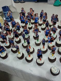 a table topped with lots of cupcakes covered in frosting and figurines