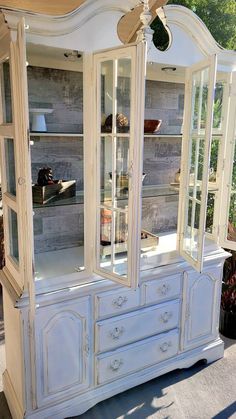 a white china cabinet with glass doors and drawers