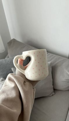 a stuffed animal with a coffee cup on its head sitting on a couch in front of a window