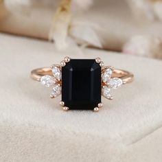 an engagement ring with a black stone surrounded by three white diamonds on top of it