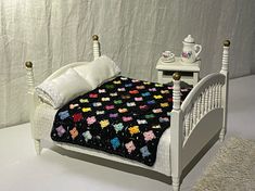 a white bed topped with a black blanket next to a night stand and nightstands