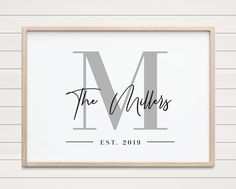 a framed print with the letter m in cursive font, on a white wall